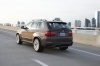 Driving 2013 BMW X5 xDrive50i in Sparkling Bronze Metallic from a rear left view